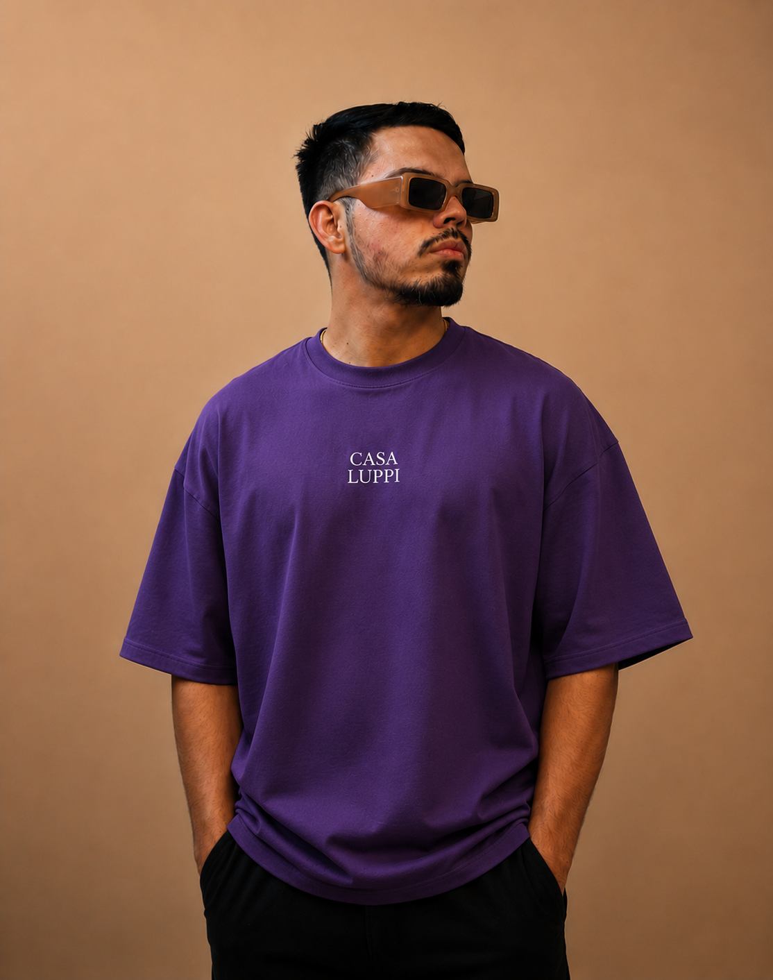 DJ Dooug de óculos escuros e camiseta roxa em fundo de estúdio
